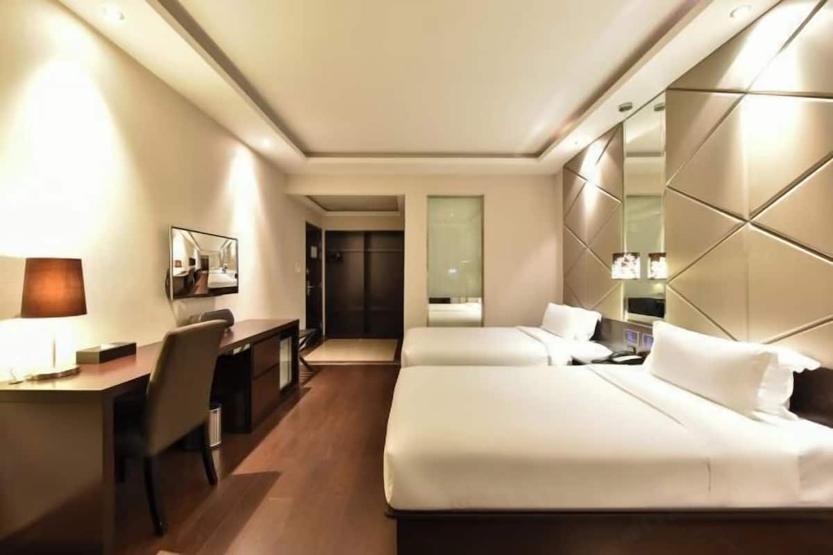 A hotel room with a bed, desk, chair, and a mirror.
