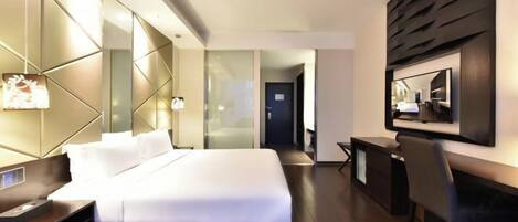 A modern hotel room with a large bed, bedside tables, a desk, and a chair.