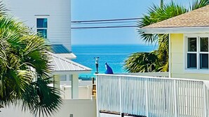 Una casa frente al mar, con vista al océano, una cerca de madera y un paraguas azul.