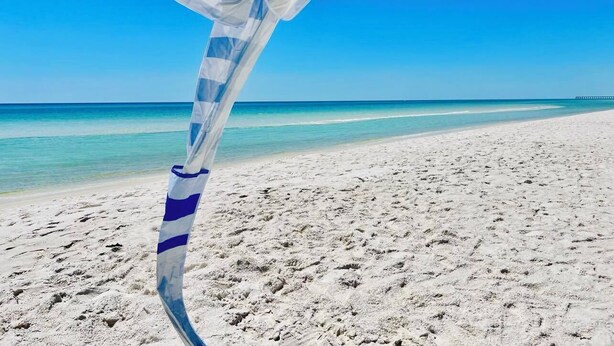 Una playa con cielo azul despejado y orilla arenosa.