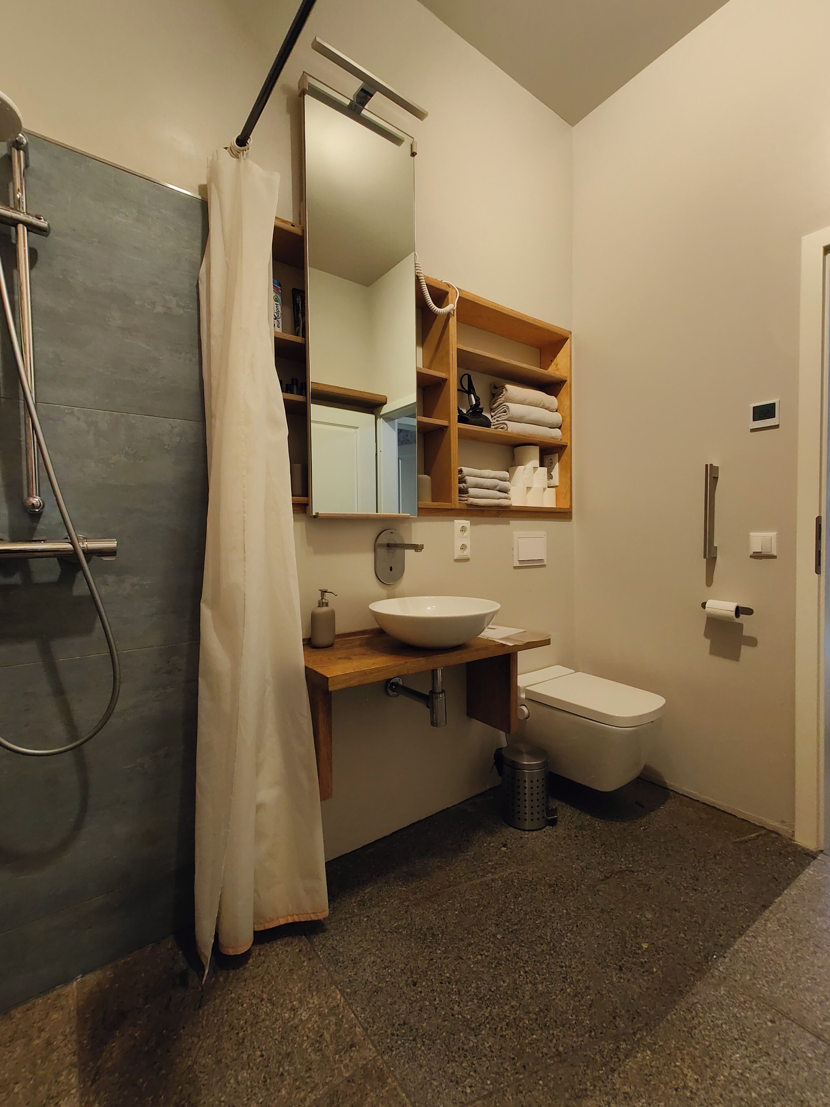 Ein Badezimmer mit Dusche, Waschbecken, Toilette und Spiegel.