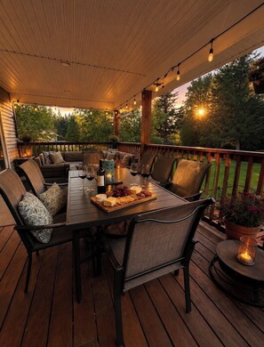 An outdoor deck with a wooden table, chairs, and a variety of food and drinks. - Caribou Lodge ~ Entire private home with hot tub! (Terrace)