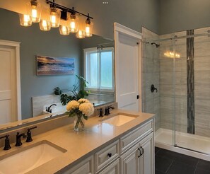 A bathroom with two sinks, a large mirror, a shower with glass doors, and a hanging light fixture. - Caribou Lodge ~ Entire private home with hot tub! (Terrace)