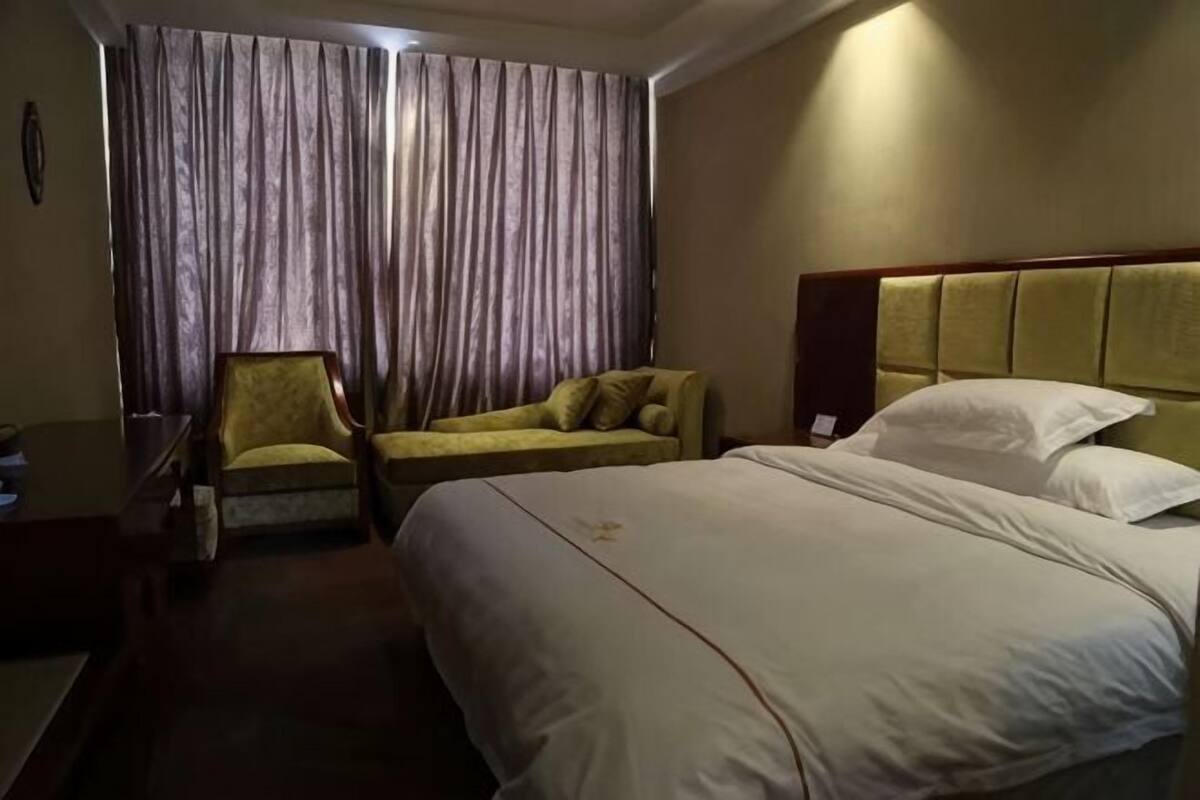 Une chambre d’hôtel avec un lit, une chaise, un canapé et des rideaux.