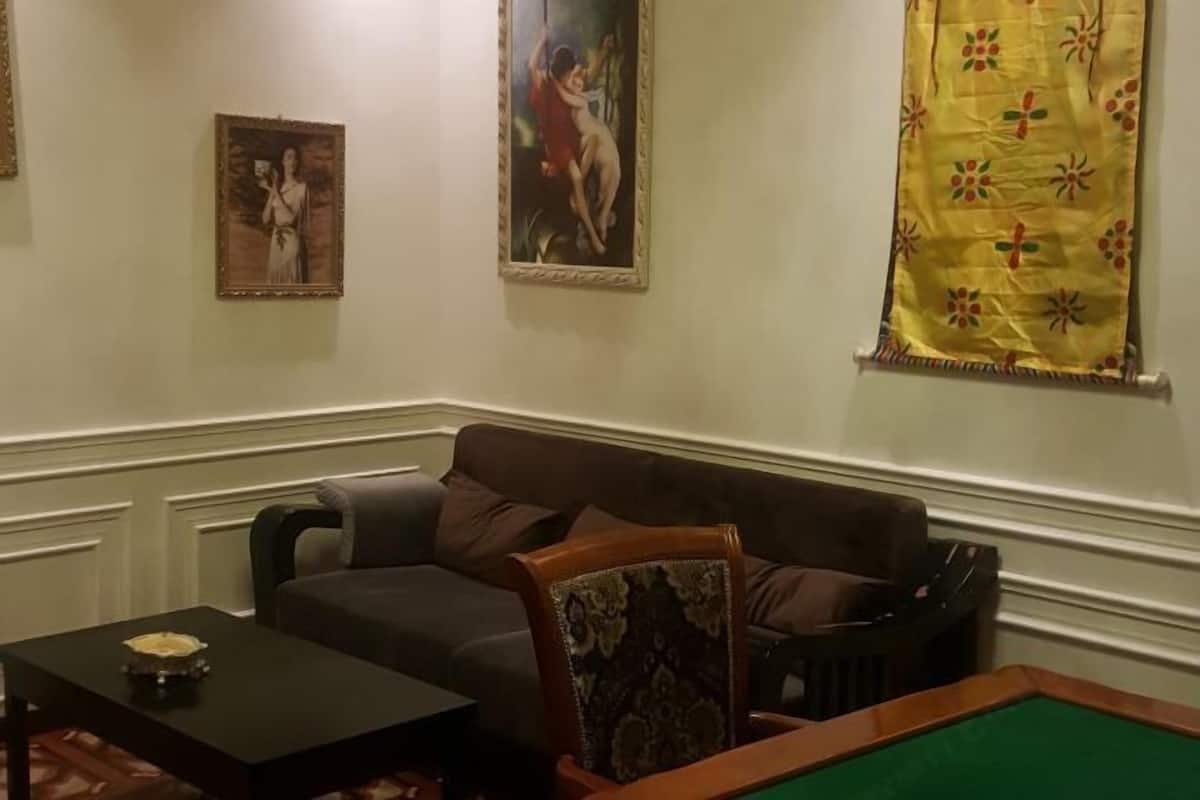 Un salon avec un canapé marron, une petite table ornée d’un objet décoratif et une table de billard.