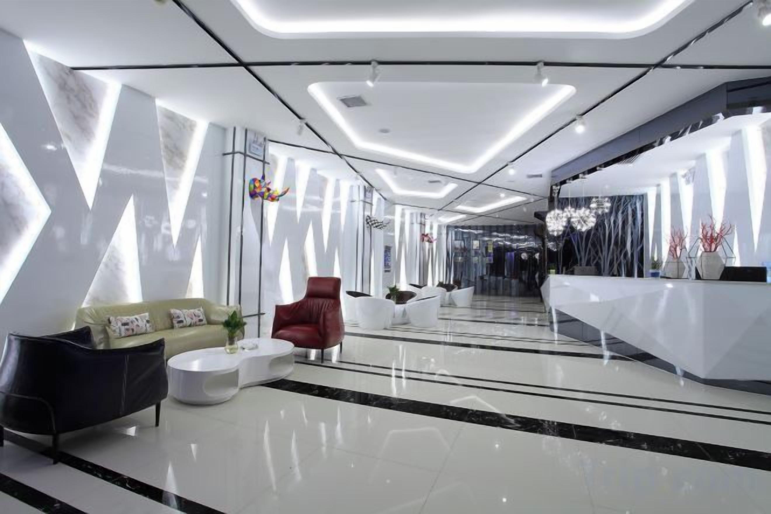 Un moderno vestíbulo de hotel con mostrador de recepción, área de estar y escalera que conduce a otras plantas.