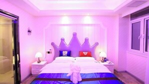 A hotel room with a large bed, two nightstands, and a plush toy on the bed.