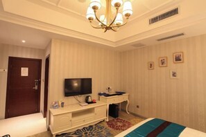 A hotel room with a bed, a television, a desk with a chair, and a dresser. - Anlong Aishang Boutique Hotel (Anlong)