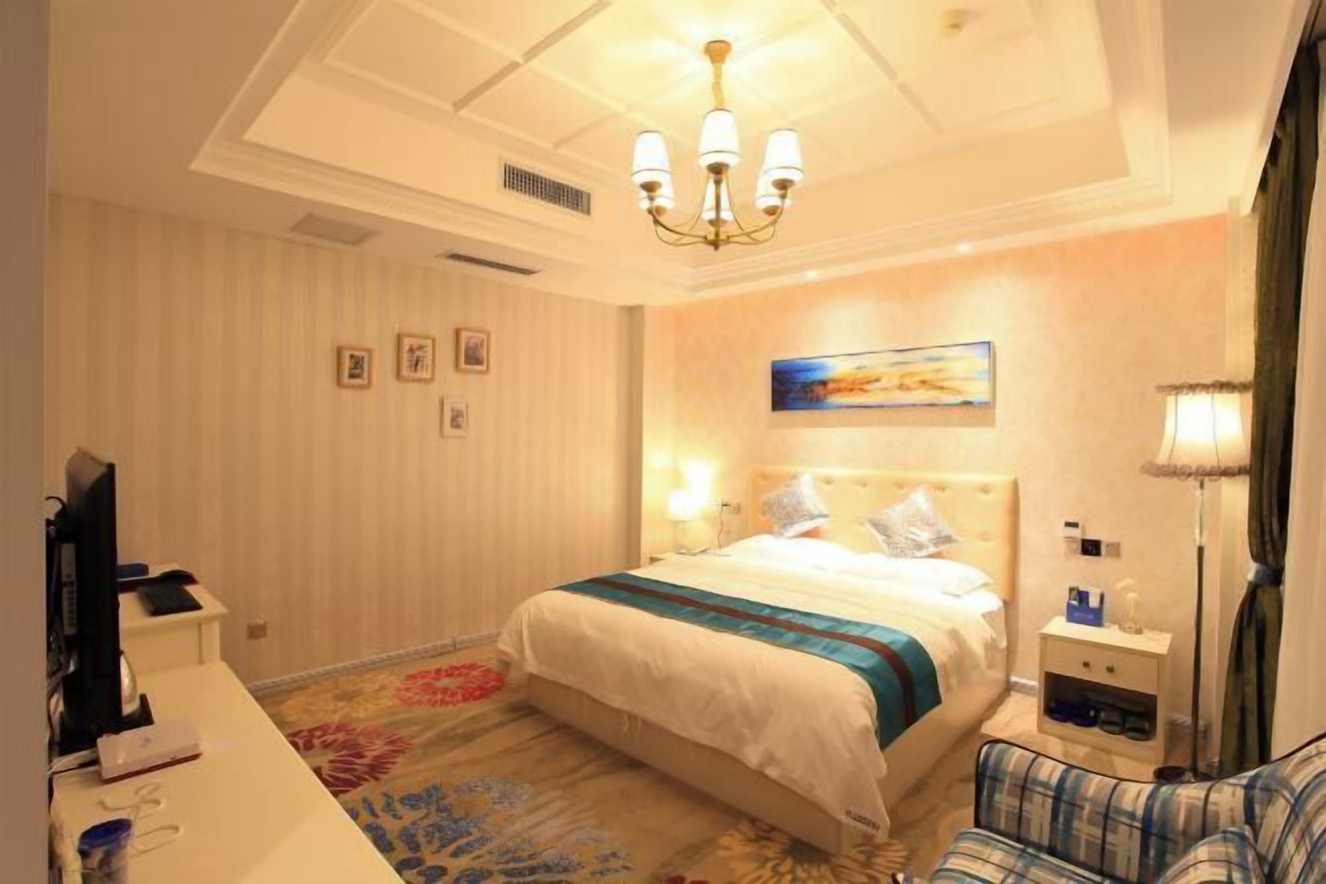 Ein Hotelzimmer mit einem Bett, einem Schreibtisch, einem Sessel, einem Fernseher und einem Bild an der Wand.
