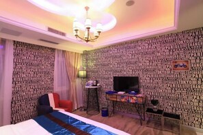 A hotel room with a bed, a TV, a small table, and a wall with city names. - Anlong Aishang Boutique Hotel (Anlong)