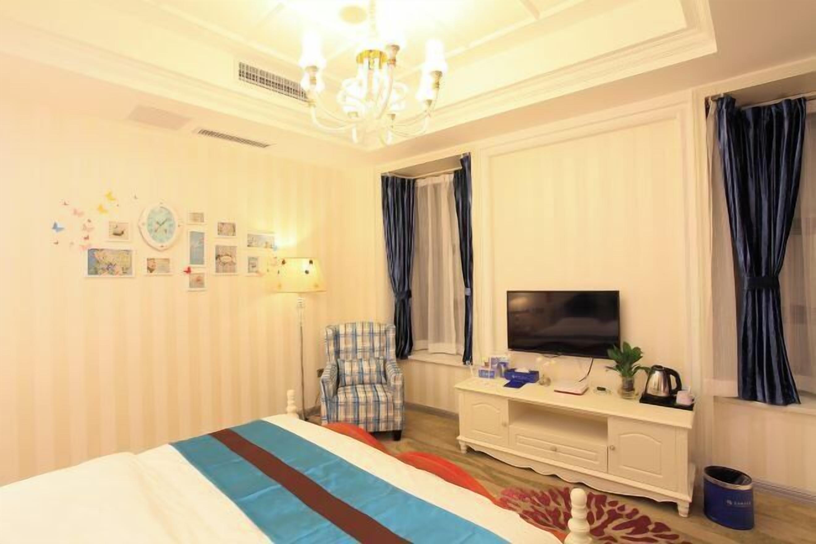 A hotel room with a bed, a television, a chair, a desk, and a window with curtains.