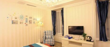 A hotel room with a bed, a television, a chair, a desk, and a window with curtains.