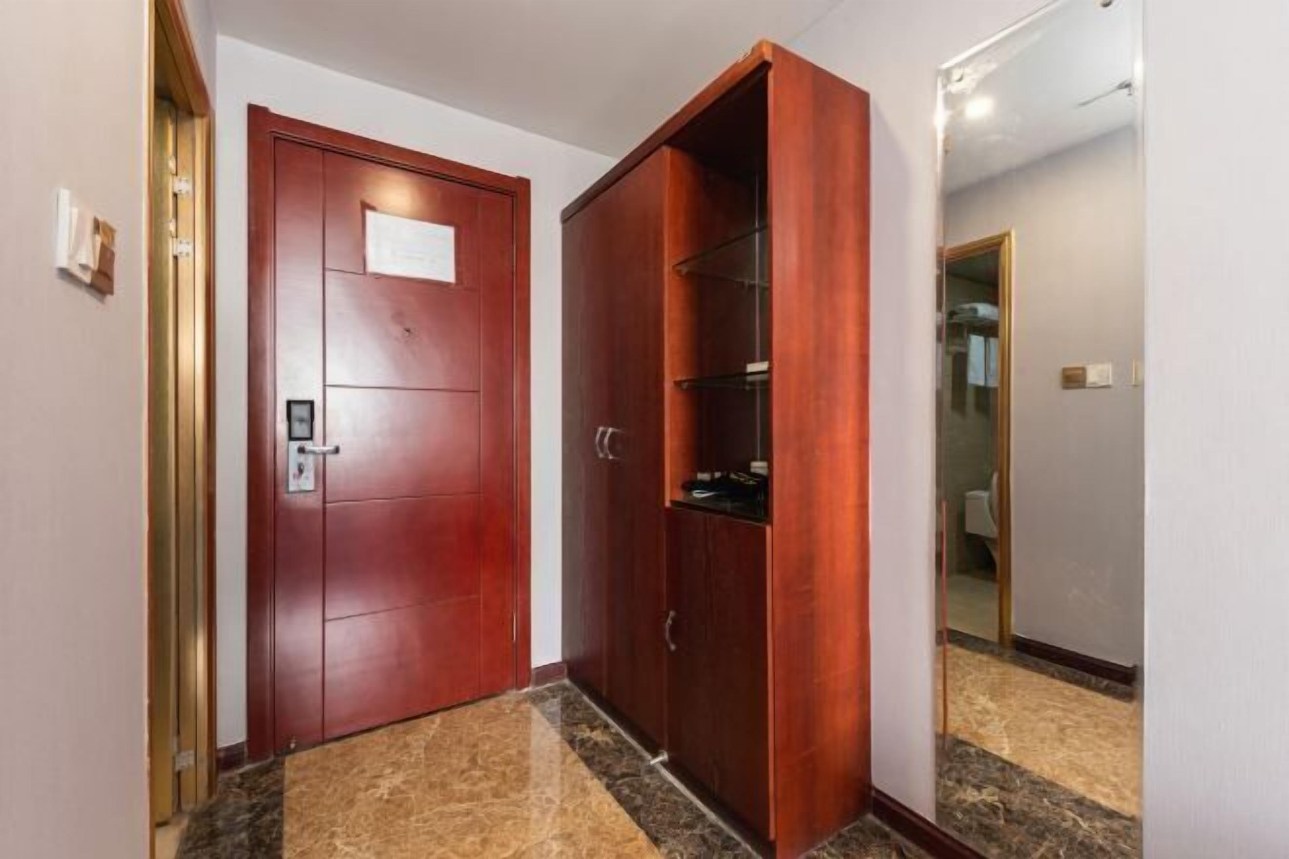 A hallway with a red door, a wooden wardrobe, and a mirror on the wall.