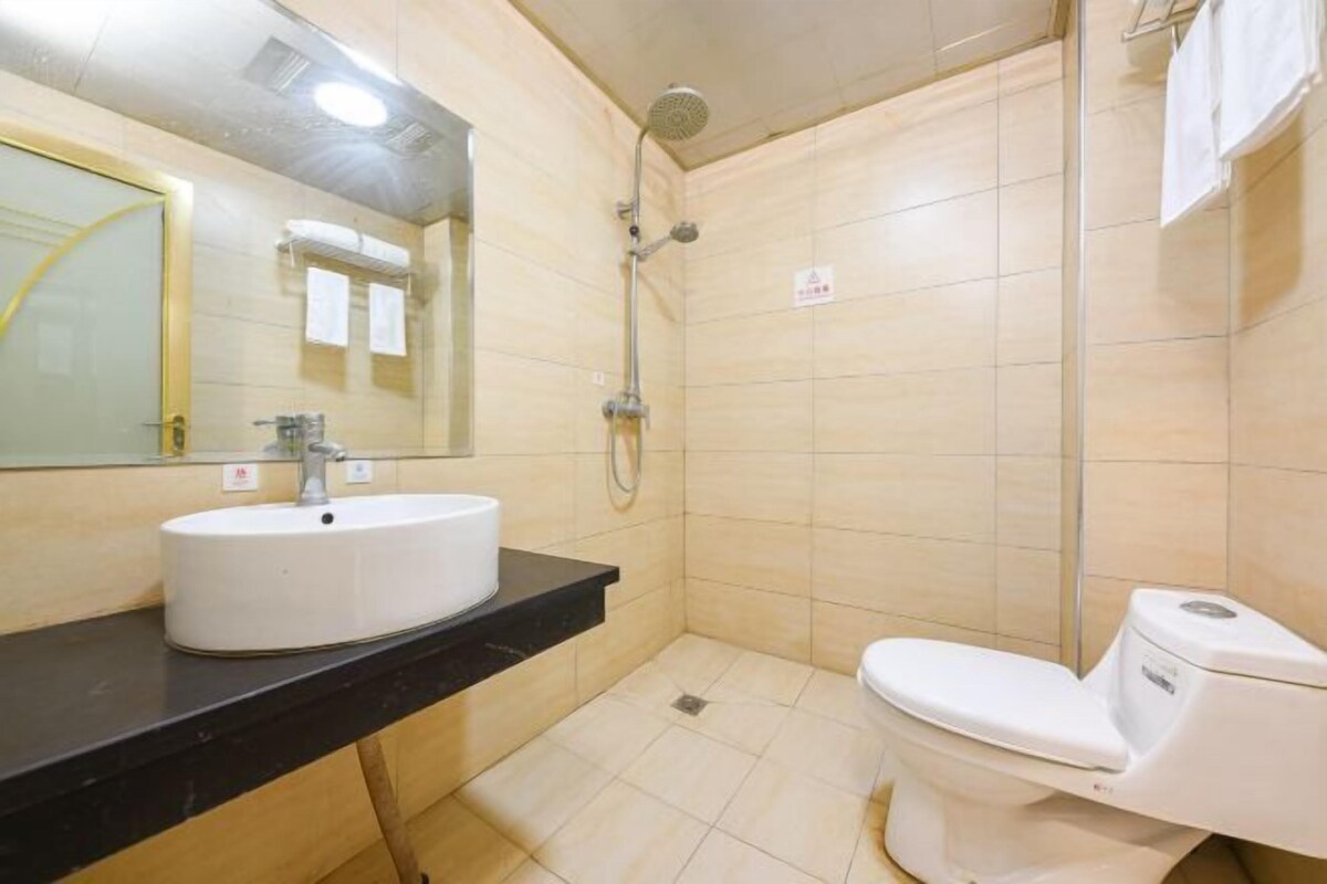 Een kleine, schone badkamer met een witte wastafel, toilet en douche.