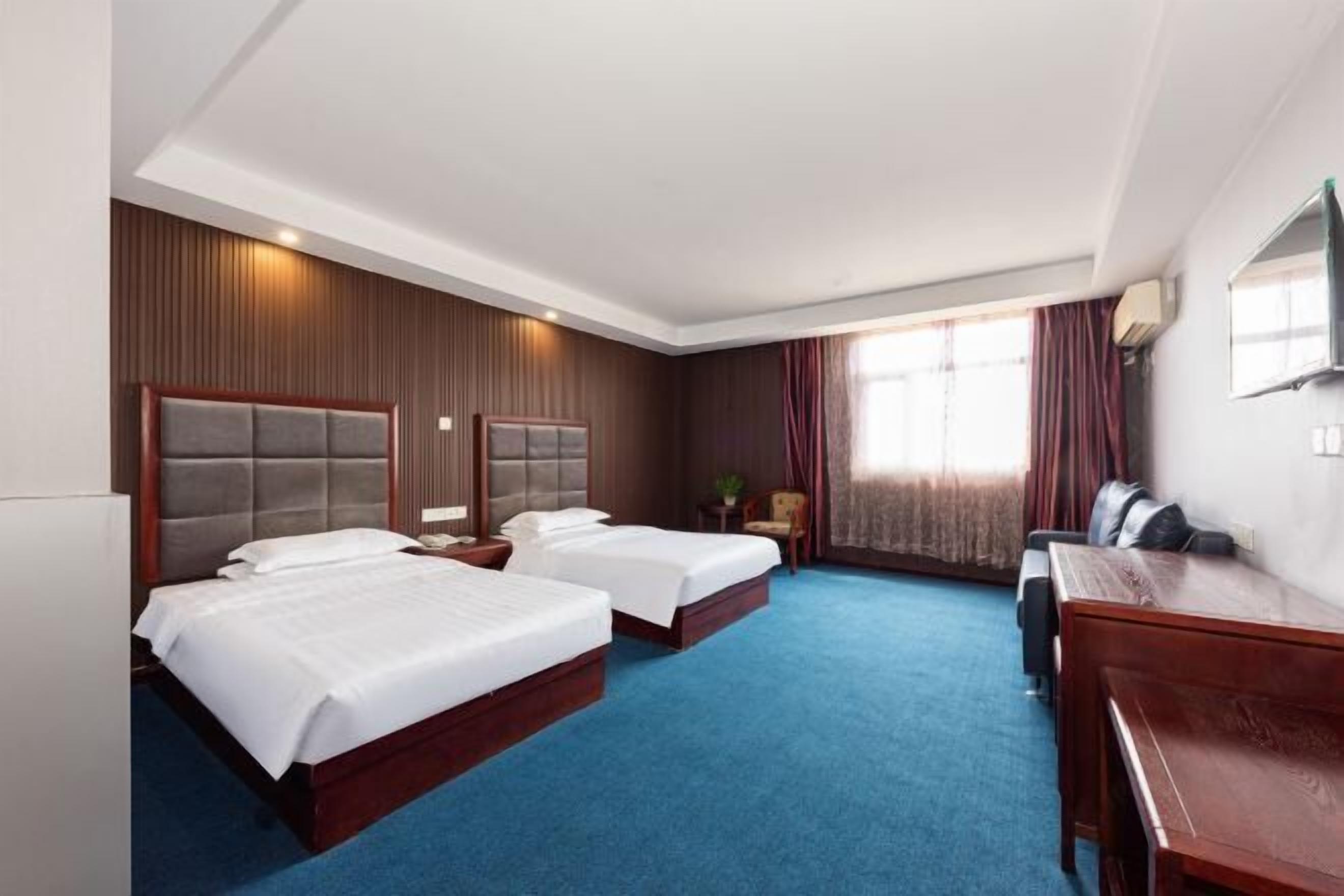 Une chambre d’hôtel avec deux lits, un bureau et une télévision.