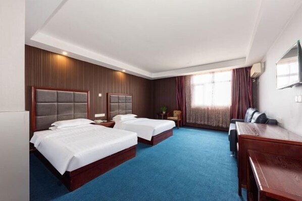 Een hotelkamer met twee bedden, een bureau en een televisie.