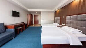 Una habitación de hotel con una cama, un escritorio, una silla y un televisor en la pared.