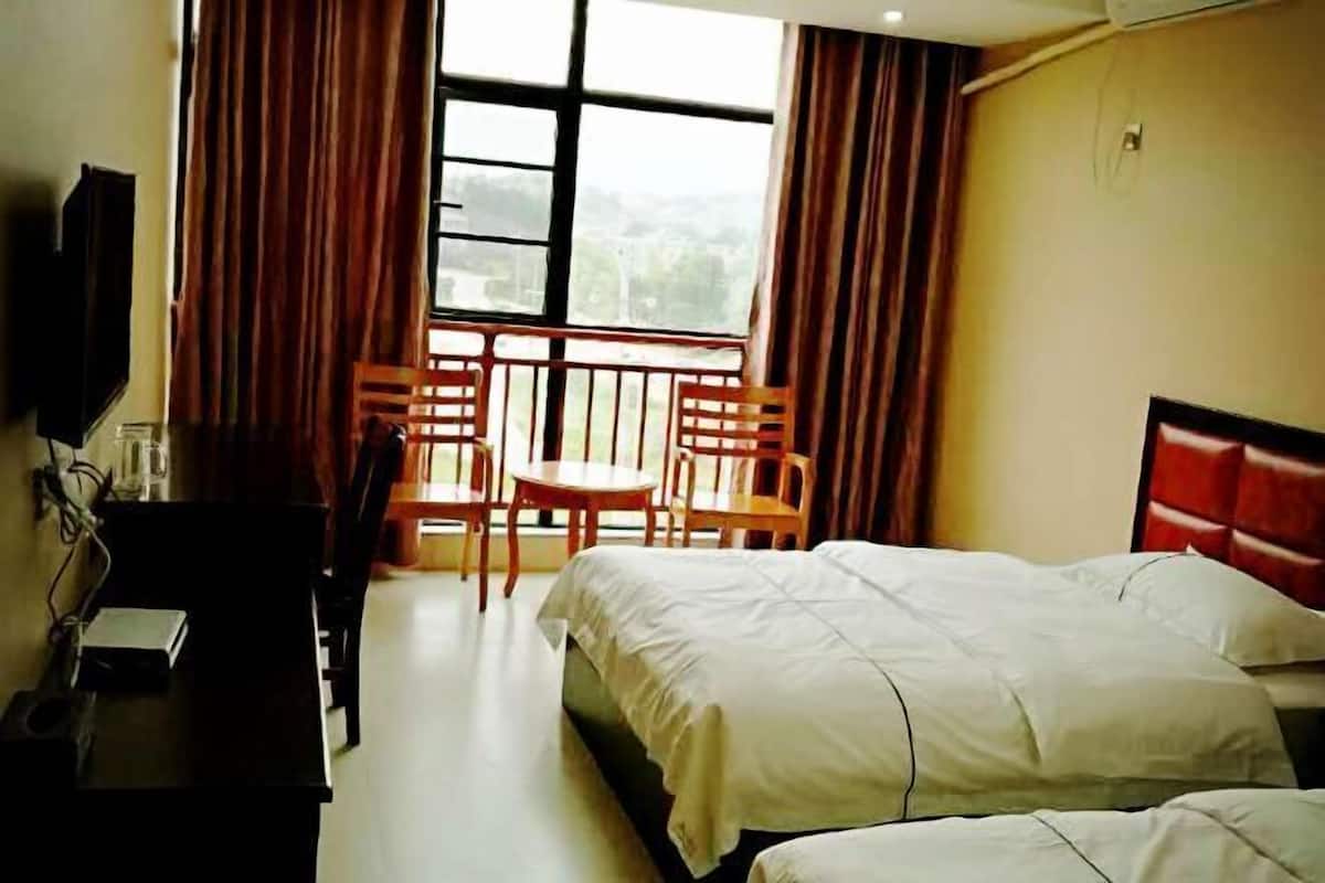 Ein Hotelzimmer mit Bett, Schreibtisch, Stuhl und einem Vorhangfenster.