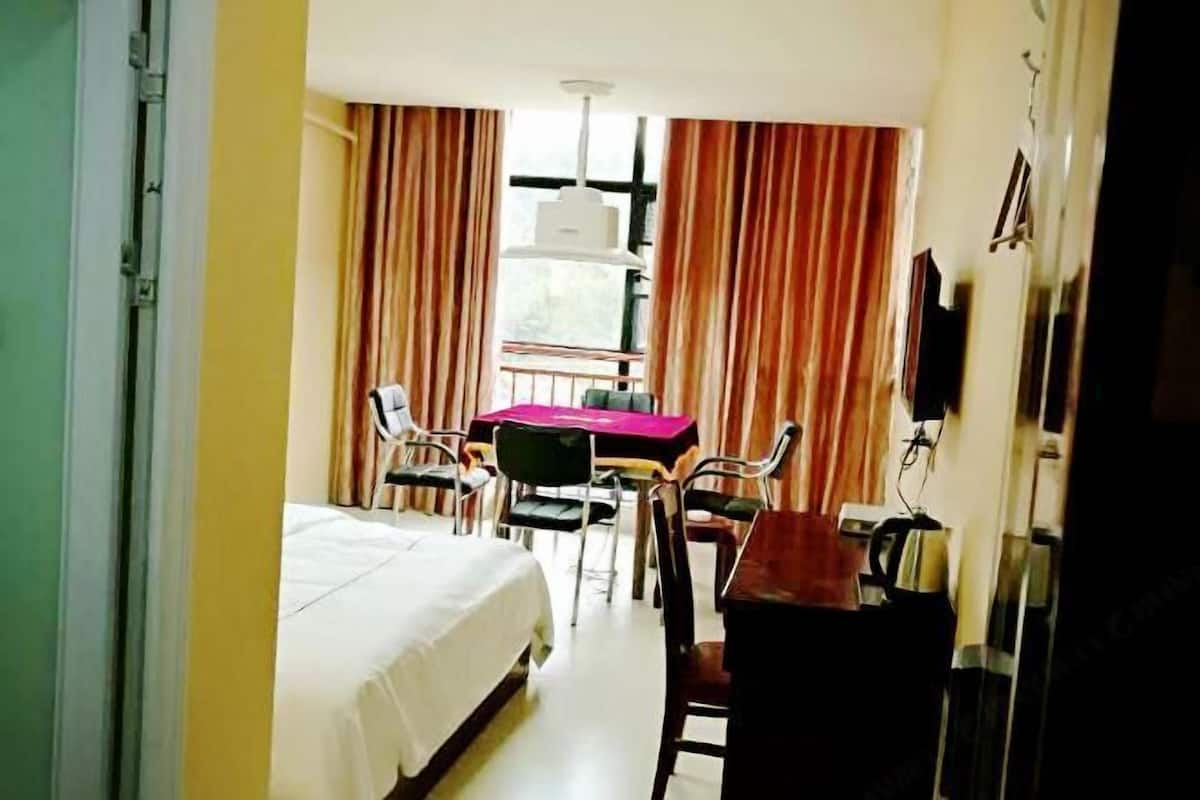 Ein Hotelzimmer mit einem Bett, einem Tisch mit Stühlen, einem Fernseher und Vorhängen.
