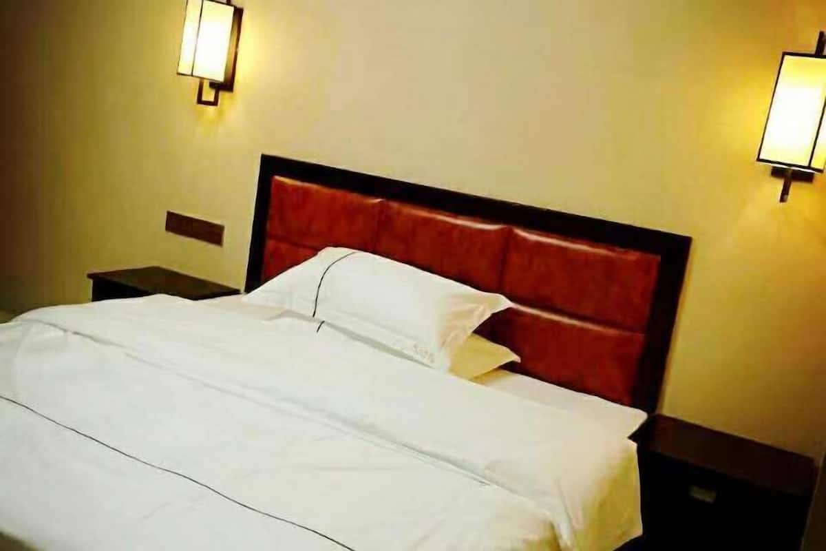 Ein Hotelzimmer mit Bett, Nachttischen und Wandlampen.