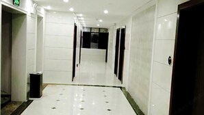 A hotel hallway with white tiled floors and doors. - Yu Shan Hua Ting Holiday Hotel (Pingjiang)