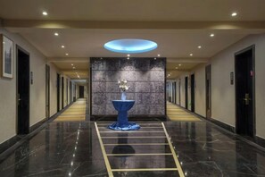 A hotel corridor with a central decorative fountain, a polished marble floor, and a series of doors on either side. - Yiju Hotel (Shanghai Chuansha Branch) (Shanghai)