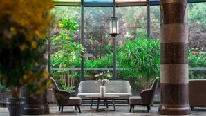 A conservatory with a sofa, two armchairs, a coffee table, and potted plants. - Yiju Hotel (Shanghai Chuansha Branch) (Shanghai)