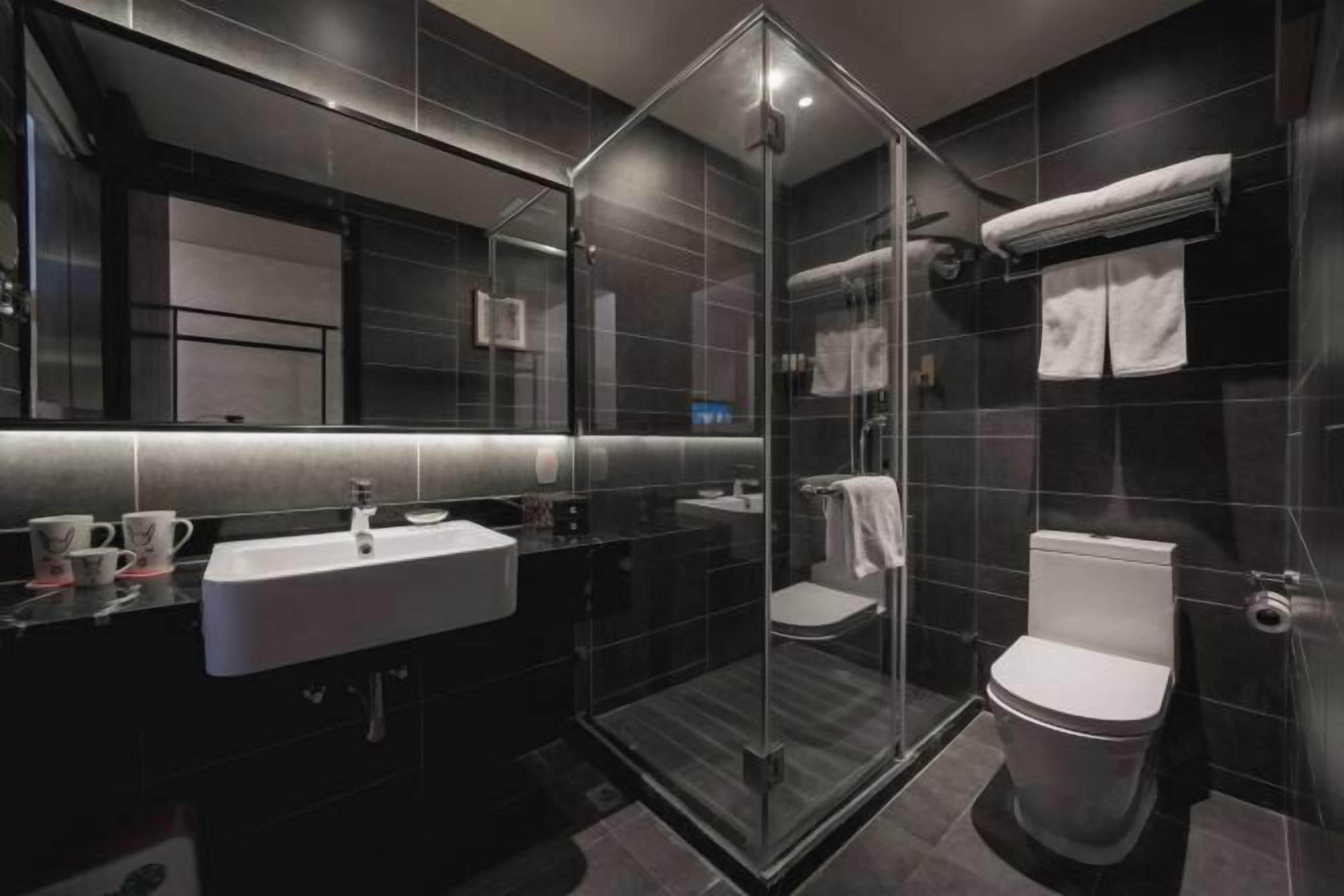 A modern bathroom with a glass-enclosed shower, a white sink, and a toilet.