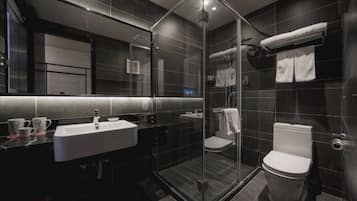 A modern bathroom with a glass-enclosed shower, a white sink, and a toilet.