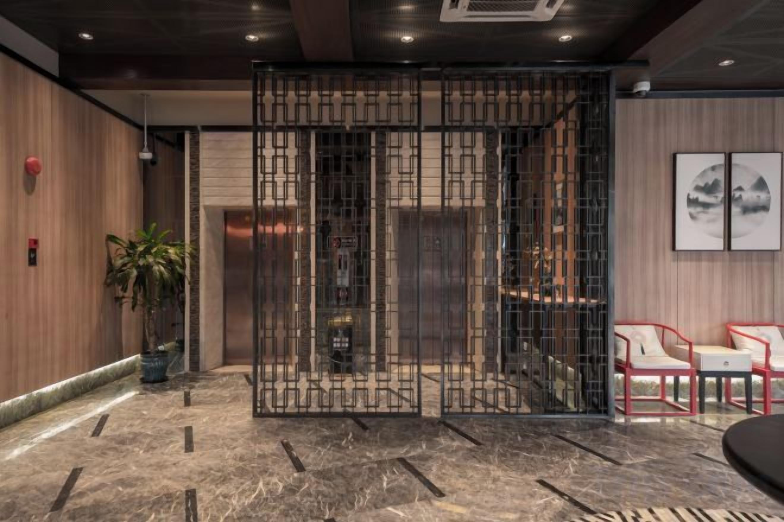 A lobby with a reception desk, seating area, and a decorative screen.