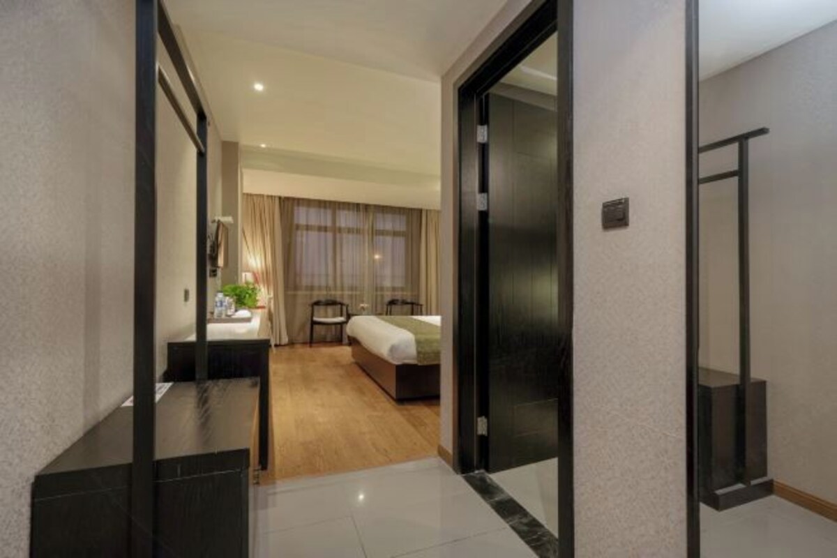 A hotel room with a bed, bedside table, and a window with curtains.