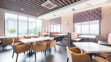 Um restaurante com mesas, cadeiras, janelas amplas e decoração moderna.