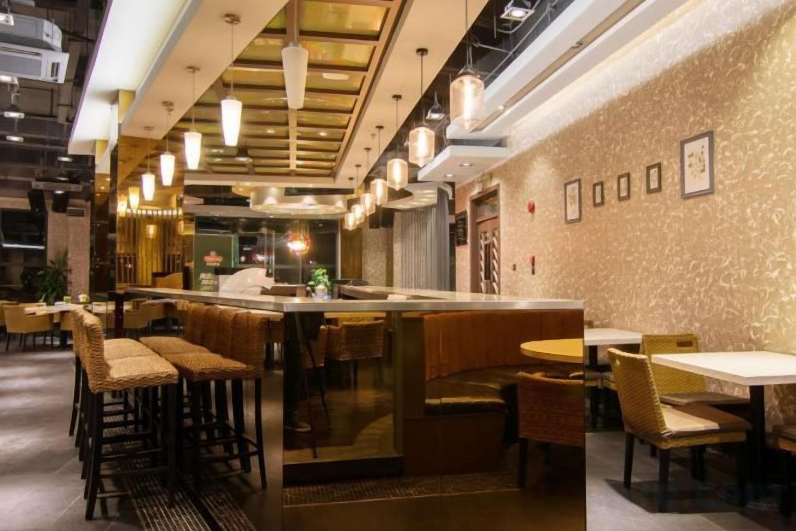 En restauranginteriör med en bardisk, sittplatser och hängande lampor.