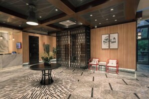 A lobby with a reception desk, a round table, two chairs, a decorative plant, and a large window. - Yiju Hotel (Shanghai Chuansha Branch) (Shanghai)