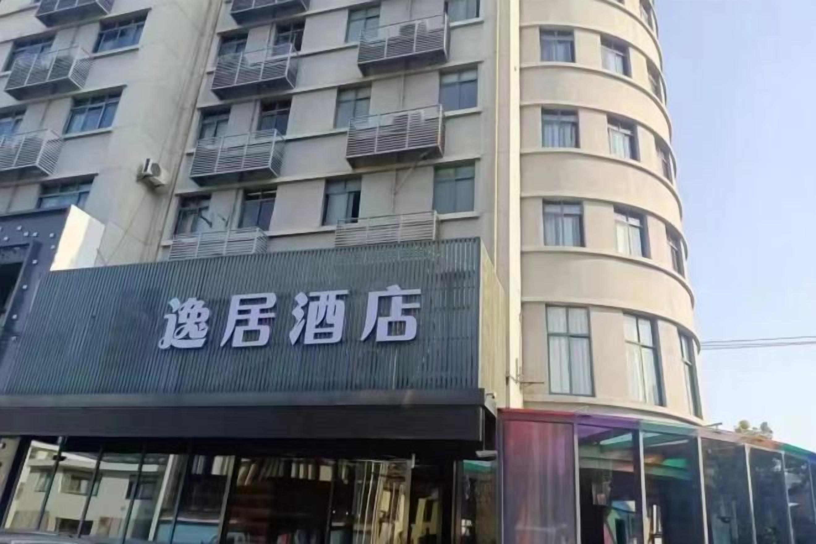 A hotel with a sign that reads '逸居酒店' on the facade.