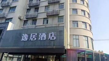 A hotel with a sign that reads '逸居酒店' on the facade.