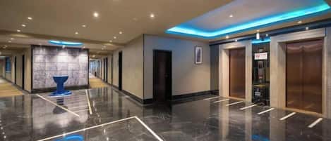 A hotel lobby with a marble floor, a reception desk, and a blue decorative piece.