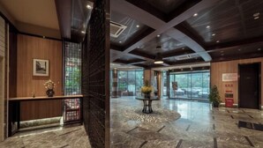 A spacious lobby with a marble floor, a reception desk, and a large window offering a view of parked cars outside. - Yiju Hotel (Shanghai Chuansha Branch) (Shanghai)