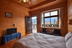 A wooden room with a bed, a TV on a table, a window with a view, and a door leading outside. - Beverly Hills (Nantou)