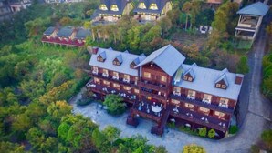A large, multi-story wooden building with balconies, surrounded by dense greenery. - Beverly Hills (Nantou)