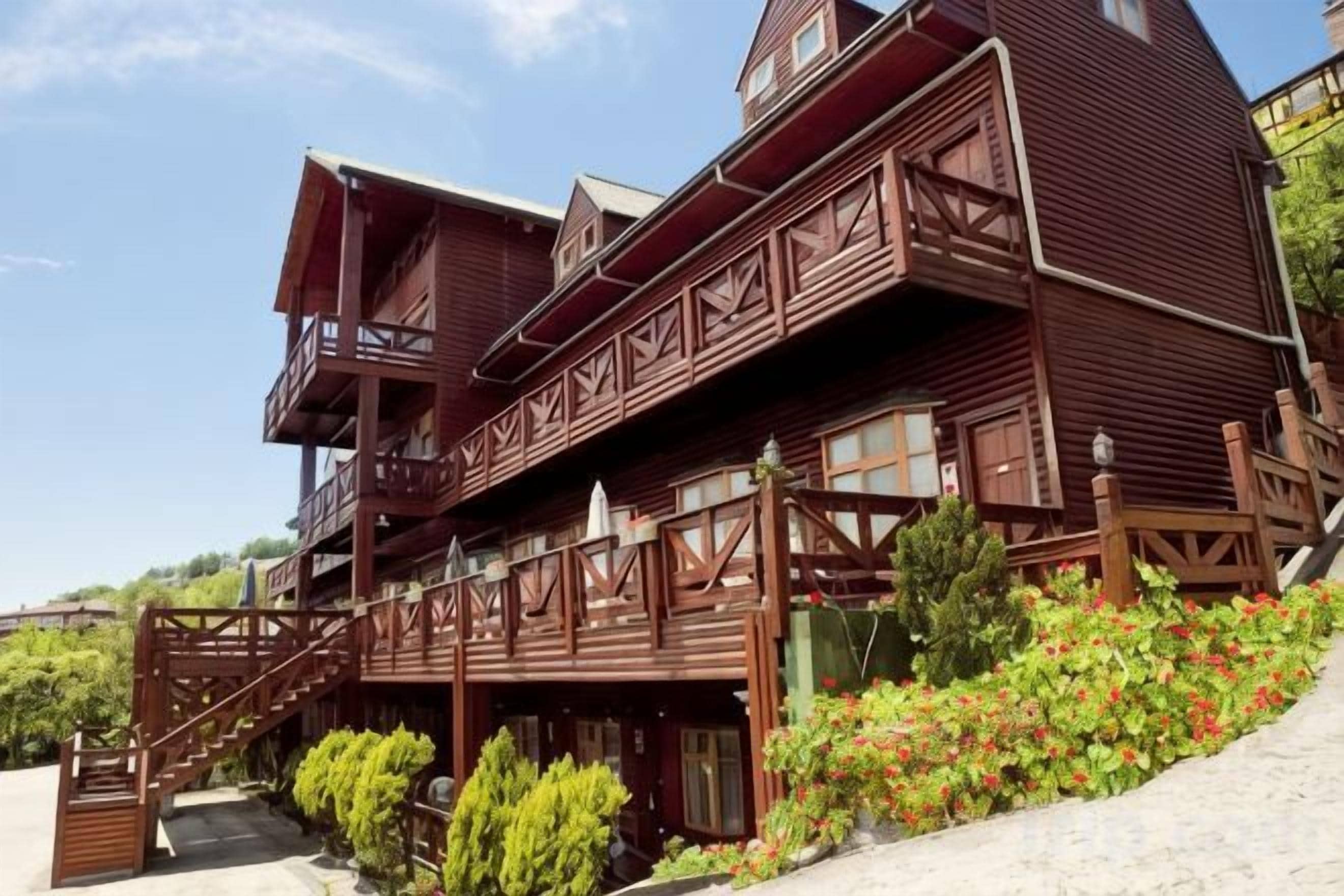 A multi-story wooden building with balconies and a staircase leading to the entrance.