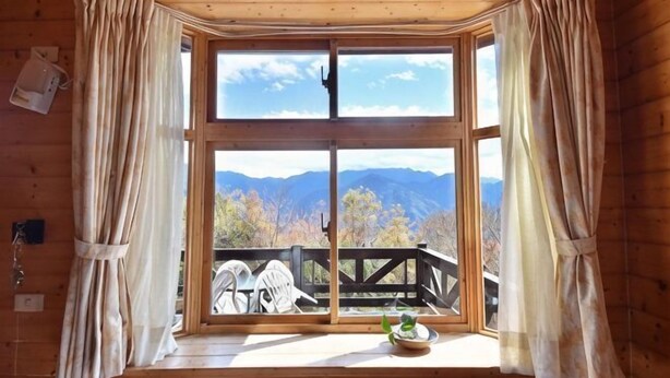 A room with a large window, wooden walls, and a view of mountains. - Beverly Hills (Nantou)