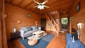 A wooden cabin interior with a sofa, coffee table, and a staircase. - Beverly Hills (Nantou)