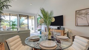 Een moderne eetruimte met een glazen tafel, witte stoelen en uitzicht op het omliggende landschap.