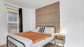 A modern bedroom with a bed, bedside table, and a decorative wall panel.
