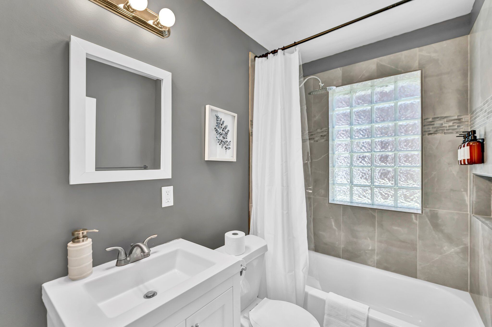 A bathroom with a large mirror, a sink, a toilet, and a shower with a glass door.