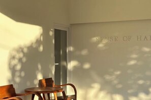 A room with a wooden table and chairs, a door, and a wall with text. - Sense of Haiya (Chiang Mai)