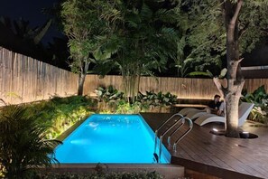 A swimming pool with a wooden deck, surrounded by tropical plants and a wooden fence. - Sense of Haiya (Chiang Mai)