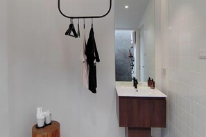 Een moderne badkamer met een wit wastafel, donkere houten opbergkast en een spiegel boven het wastafel.