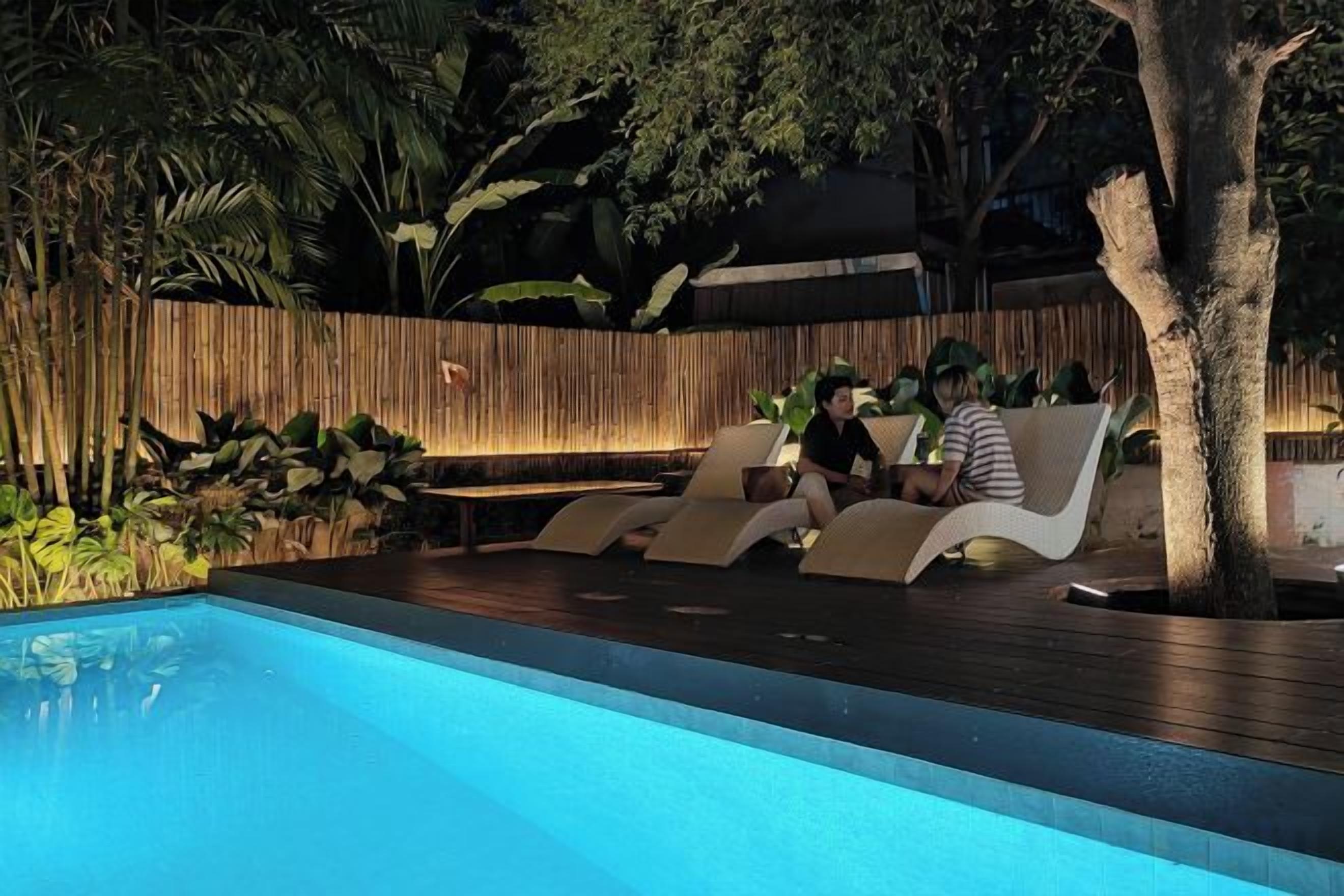 A poolside area with lounge chairs and a wooden fence.